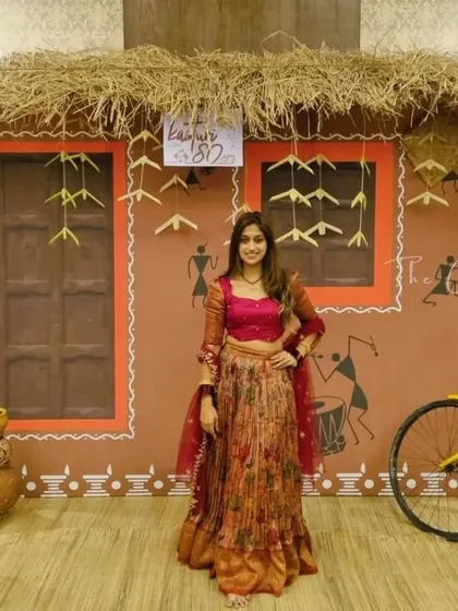 A guest poses against the rustic village house backdrop. The hand-painted Warli figures and thatched roof created an authentic and immersive photo opportunity.