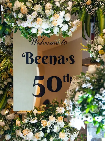 A personalized welcome sign for Beena's 50th birthday surprise party. Surrounded by an abundance of white flowers, this mirrored sign added a touch of class and made the guest of honor feel celebrated from the moment she arrived.
