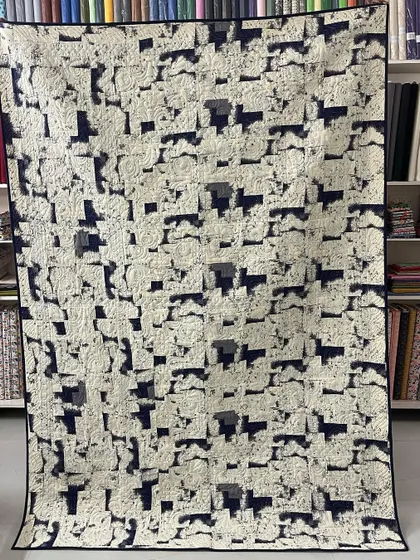 The back of a "Bear Paw" quilt, showing a subtle, low-contrast print.