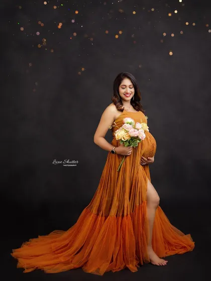 A joyful portrait in a beautiful mustard-colored gown. Holding a bouquet of flowers adds a soft, romantic touch to the overall look.
