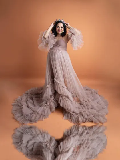 A stunning reflection shot. The mom-to-be, wearing a crown and a beautiful ruffled gown, looks like royalty in this creative and elegant portrait.