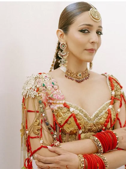 A close-up portrait of the bride, her sleekly styled hair and statement braid complementing her bold makeup and jewelry.