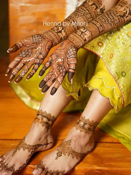A complete bridal look with intricate mehendi on both hands and feet. The foot design is a delicate anklet pattern that complements the heavy hand mehendi.