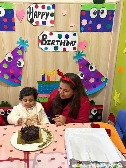 The birthday girl sits at the party table with her mother, ready to celebrate with her friends.