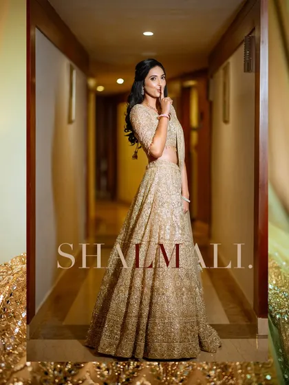 A stunning portrait of the bride in a magnificent golden lehenga. The photo is framed to emphasize the grandeur and intricate detail of her traditional outfit.