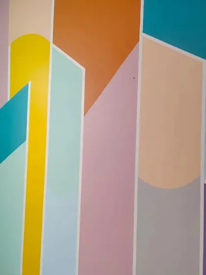 A close-up of a colorful geometric wall design, using a playful palette of pastel and bright colors like yellow, orange, and teal for a vibrant effect.