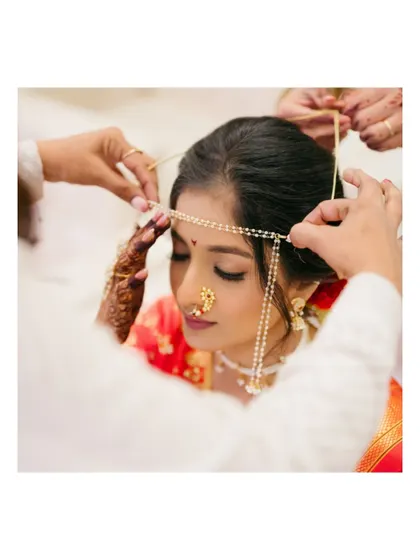 A close-up shot focusing on the 'mundavalya' being tied on the bride's forehead.