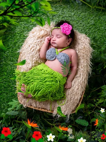 Your little one as a tropical princess. This adorable newborn is dressed in a crocheted mermaid-style outfit, sleeping peacefully in a basket surrounded by lush greenery.
