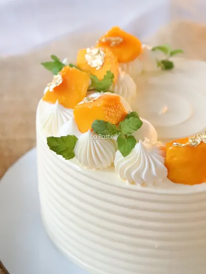 This is my Alphonso mango cake, decorated with fresh mango chunks, mint leaves, and a touch of gold leaf.