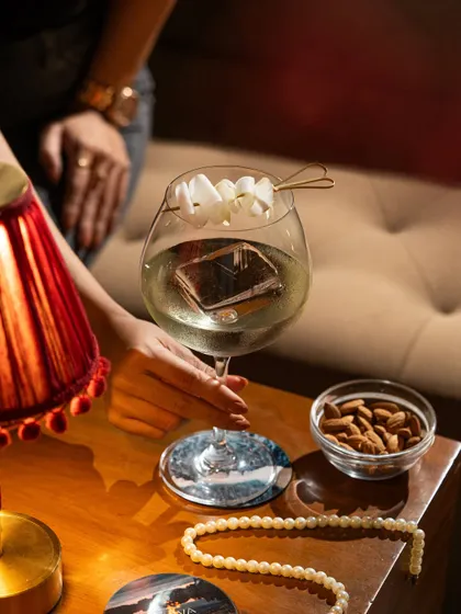 A sophisticated martini with a unique garnish. The lighting is designed to feel like an intimate evening at a chic bar.