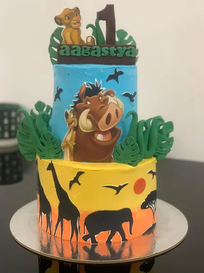 Hakuna Matata! A vibrant two-tier Lion King themed cake for a first birthday. The bottom tier shows a beautiful sunset silhouette, while the top features Simba and Pumbaa.