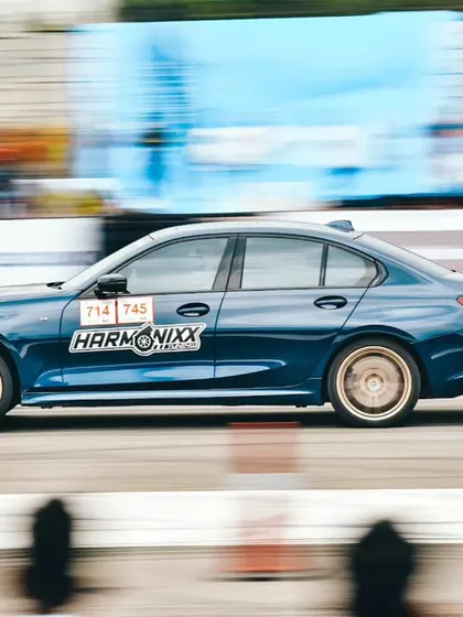 A blue BMW 3-series with Harmonixx branding, captured in a perfect panning shot. This demonstrates how sponsors can get dynamic brand visibility on cars competing in the races.