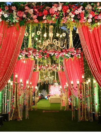 An entrance fit for royalty. I used dramatic red drapes, floral arches, and grand candelabras to create a luxurious and theatrical walkway for an opulent wedding celebration.