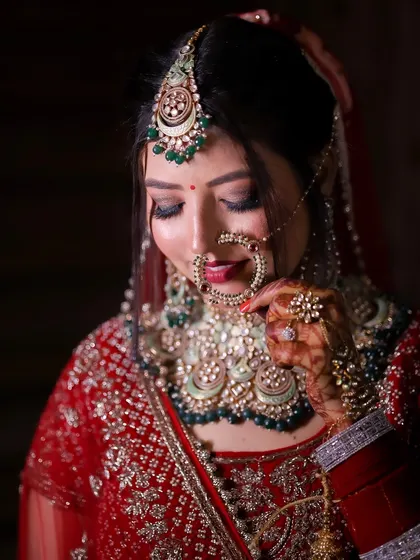 A beautiful, three-quarter portrait of the bride, highlighting her holding her nose ring. It's a classic, graceful pose that emphasizes her traditional jewelry.