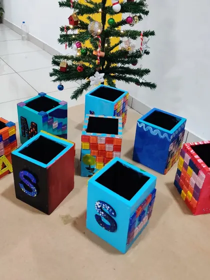 A collection of uniquely decorated pen stands, personalized with initials and colorful patterns, drying after a fun birthday party.