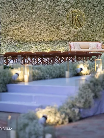 An ethereal all-white reception. The aisle and backdrop are adorned with clouds of baby's breath, while flickering candles cast a warm, romantic glow, creating a scene straight out of a fairy tale.