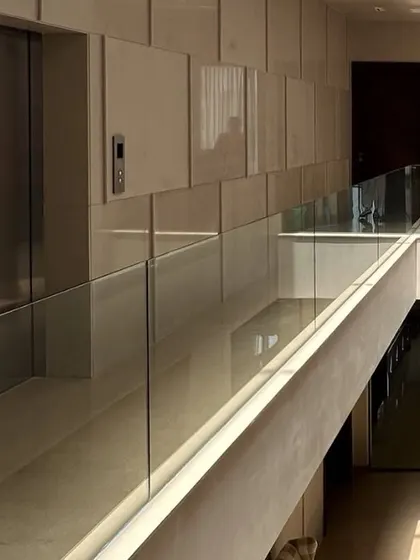 The upper-level corridor in The Brick House features a double-height space with a glass railing, creating a visual connection to the ground floor. The clean lines of the architecture provide a backdrop for the client's art collection.