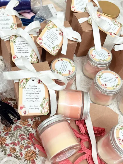 The process of packaging the peach-themed ombré candles for the baby shower. Each one was boxed with a custom tag and white satin ribbon.