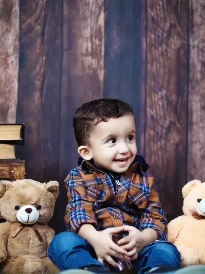 A toddler boy sitting with his teddy bear friends during his second birthday photoshoot.