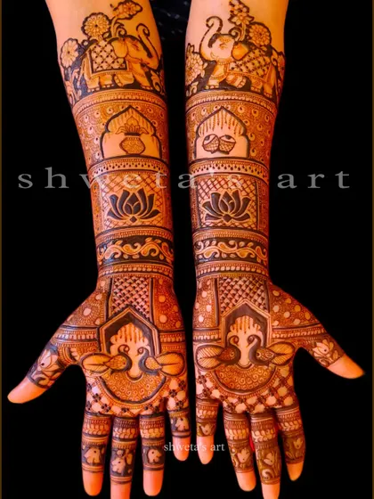 A beautiful example of a full-arm bridal design. The pattern includes bands of elephants, a kalash, and lotus flowers, with peacocks adorning the palms.