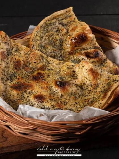 Here, I'm showcasing a different variety of naan. The dark background makes the bread's golden-brown color and the texture from the herbs stand out.