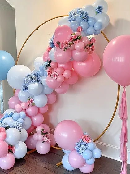 A lovely gender reveal or baby shower setup. The gold ring is adorned with pink and blue balloons and delicate floral accents, creating a beautiful and balanced design.