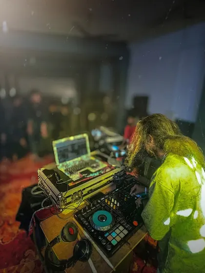 A moody, atmospheric shot of me at my DJ setup during a college event, with light filtering through the haze.