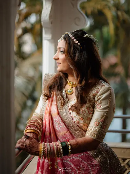 A thoughtful portrait of the bride looking out from a balcony, her traditional jewelry and attire looking stunning in the natural light.