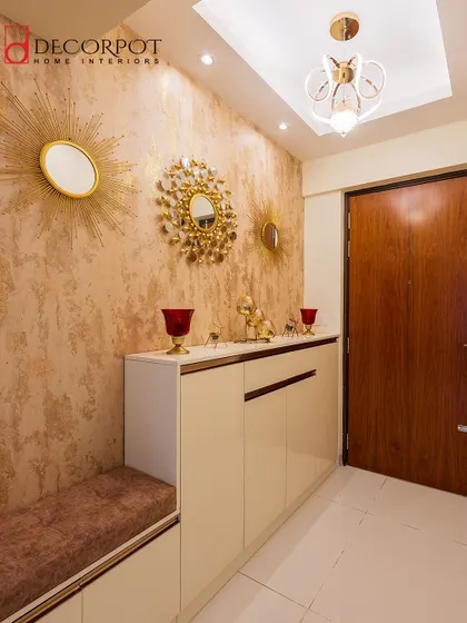 A glamorous foyer with textured wallpaper and decorative mirrors. The shoe cabinet with an integrated seater provides a practical and stylish solution for the entryway.