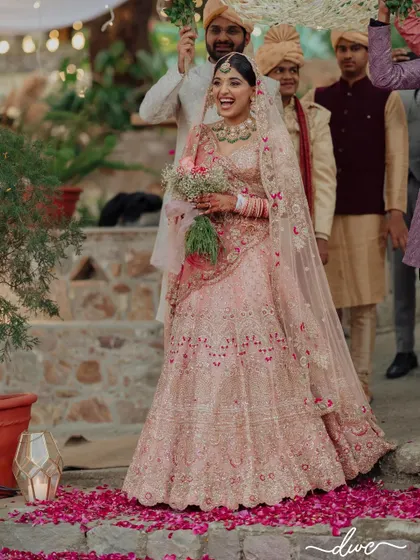 The bride's joyful, candid laugh as she makes her entrance, walking down an aisle of scattered petals at her beautiful lakeside wedding.