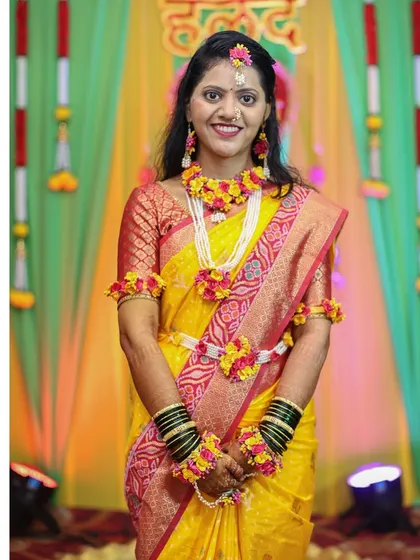 A portrait of the bride in a yellow saree and floral jewellery for her Haldi ceremony.