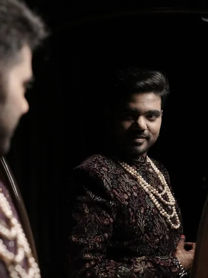 The groom catches his reflection in the mirror, a classic and introspective shot before the main event.