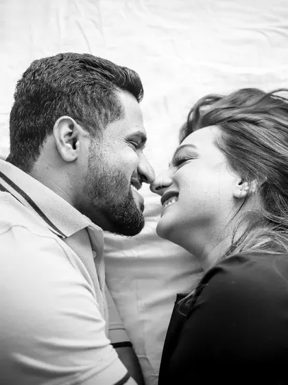 An intimate and romantic black and white shot from an overhead angle. This pre-wedding photo captures a quiet moment of connection as the couple looks at each other.