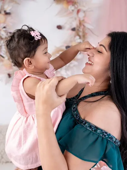 A playful moment between a mother and her daughter. The little girl gently touches her mom's nose, a sweet and innocent gesture of love.