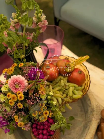 A tabletop arrangement featuring fresh fruits like grapes and pomegranates alongside flowers, adding to the natural, abundant feel.