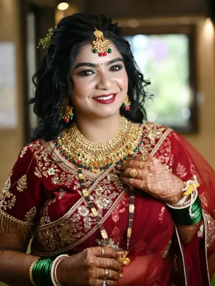 The happy bride, ready for her ceremony. Her makeup features a classic red lip and defined eyes, a perfect choice for a traditional Indian bridal look.
