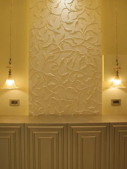 This custom-made wall panel features a hand-painted floral design with a pearl finish, created by our in-house artist. It is flanked by beautiful rivet glass pendants that cast a warm, inviting glow.