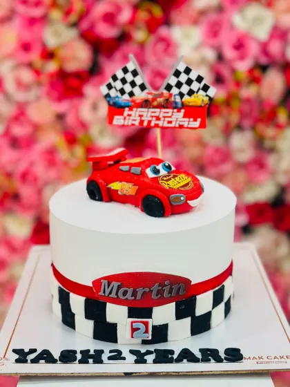 Simple yet striking, this 'Cars' themed cake features a Lightning McQueen topper and a checkered flag border. It's a great option for a smaller, themed celebration.