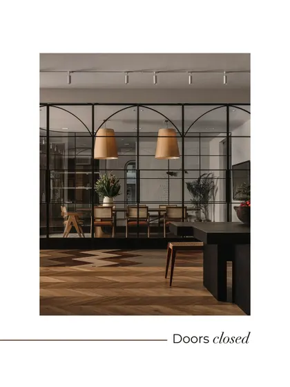 The arched, black-framed glass partitions are a key design feature, shown here with the doors closed. This creates an elegant, enclosed conference room, offering privacy without visually disconnecting from the larger showroom.