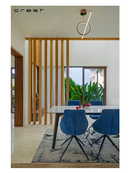 The dining area of the 'Framed House,' where a slatted wooden partition provides a degree of separation while maintaining a visual connection.