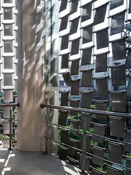 A detail shot of the 'shimmer screen,' showing how the individual steel panels are fixed to create a kinetic façade that casts moving shadows and reflects sunlight.