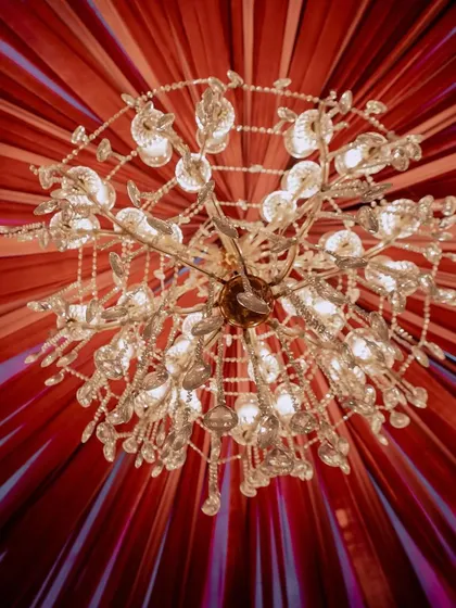 A view looking up at a custom chandelier set against a ceiling of radiating red fabric. This shows our attention to every surface, creating a complete design from floor to ceiling.
