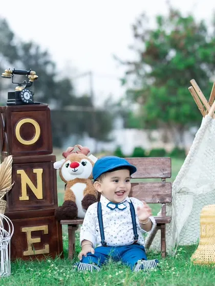 A vintage-themed outdoor first birthday party, complete with a mini teepee and an old-fashioned telephone.
