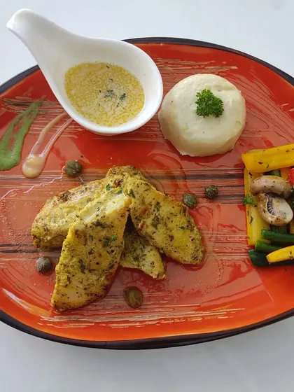 A plated meal of herb-crusted chicken, mashed potatoes, and sautéed vegetables. We provide complete, balanced meals for seated dinners.