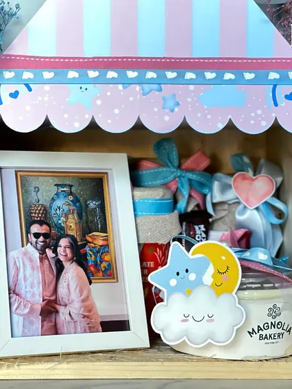 A closer look inside the parents-to-be hamper, featuring a photo frame, treats from Magnolia Bakery, and other sweet details to celebrate their journey to parenthood.