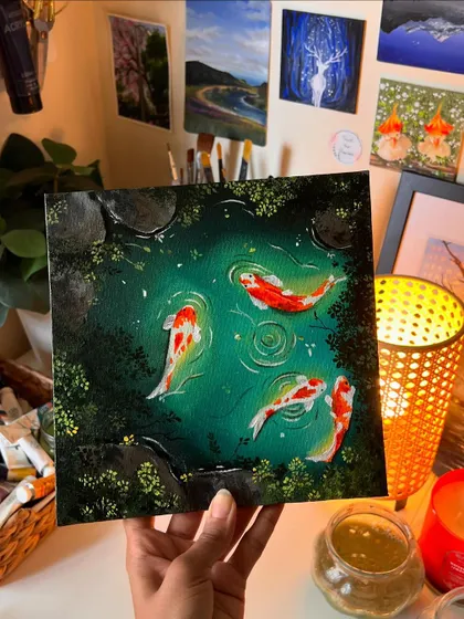 Holding the finished koi pond canvas in my studio. The warm light from my lamp highlights the glowing effect of the water.