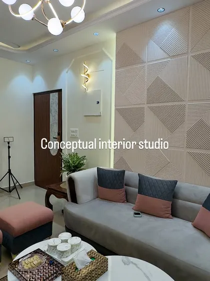 A beautiful living room with a geometric 3D wall panel. The combination of grey sofas with pink and blue cushions adds a modern and fresh look.