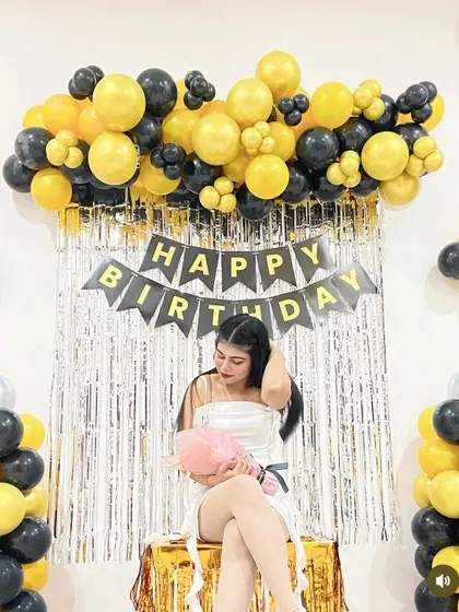 A guest poses in front of the yellow and black birthday decoration, showing how it creates a great photo opportunity.