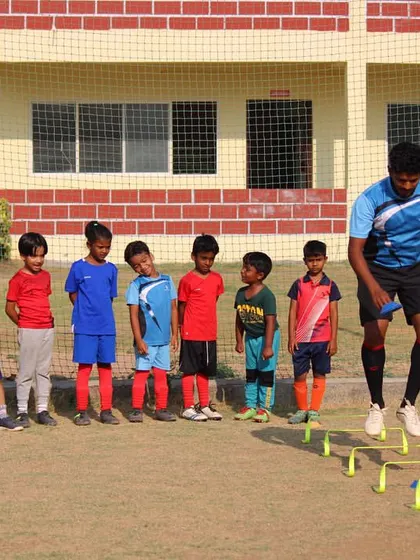 A coach demonstrates the proper technique for a hurdle jump drill as our youngest group of players watches and learns.