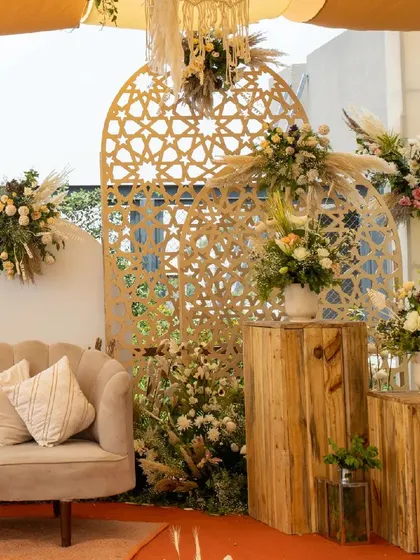 Another view of the rustic and elegant decor, with wooden block pedestals, lush floral arrangements, and a comfortable lounge sofa, creating a warm and inviting atmosphere.